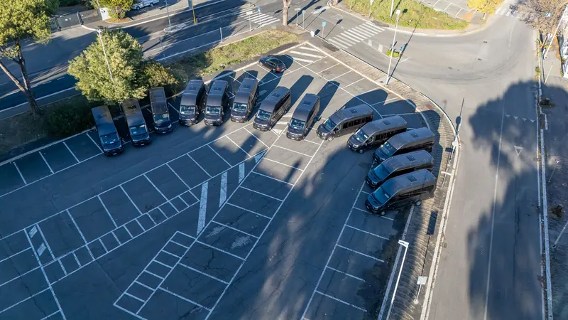 Vista dall'alto di tredici minibus neri in un parcheggio