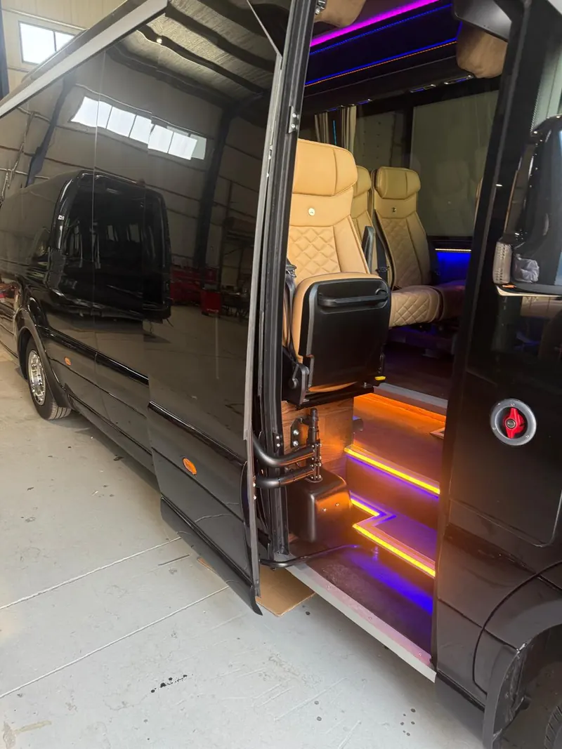 Porta laterale aperta di un minibus con gradino illuminato e sedili in pelle